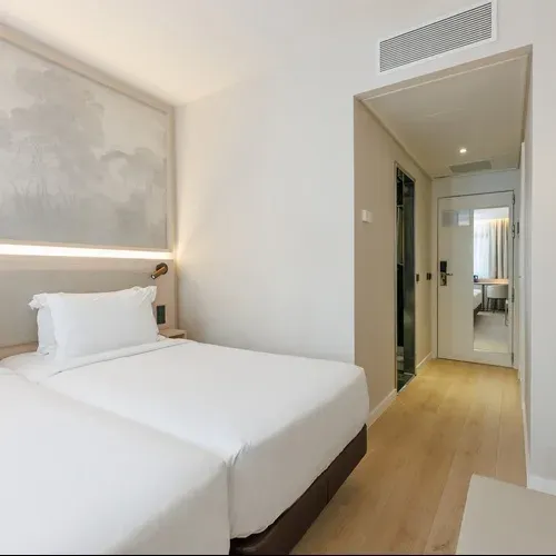 Modern hotel room with twin beds, minimalist decor, and elegant art. Hotel Vilamari Barcelona | Estival Group | Official Web