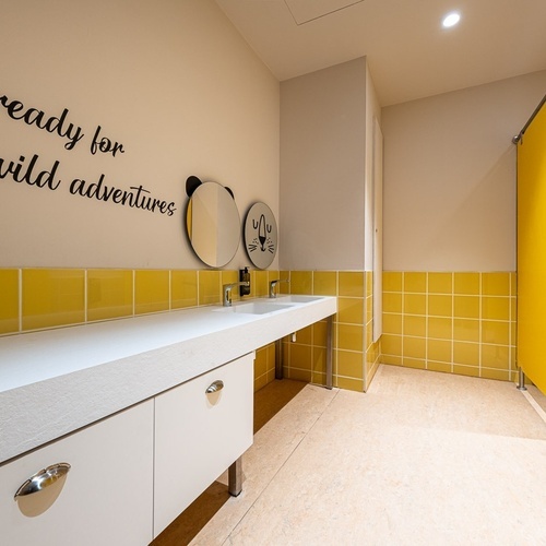a bathroom with yellow tiles and a sign that says be ready for wild adventures
