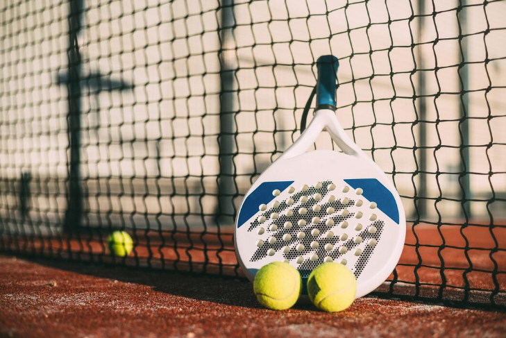 a man in a green shirt is holding a paddle on a tennis court