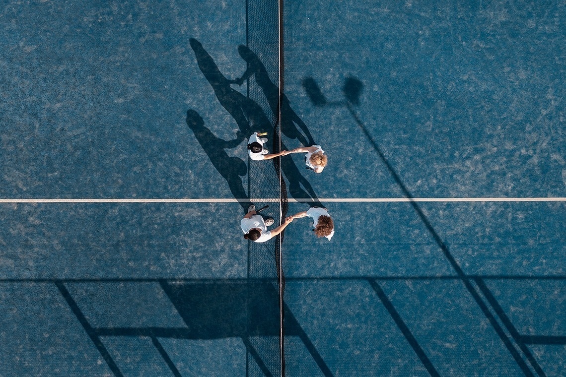 an aerial view of two people shaking hands on a tennis court