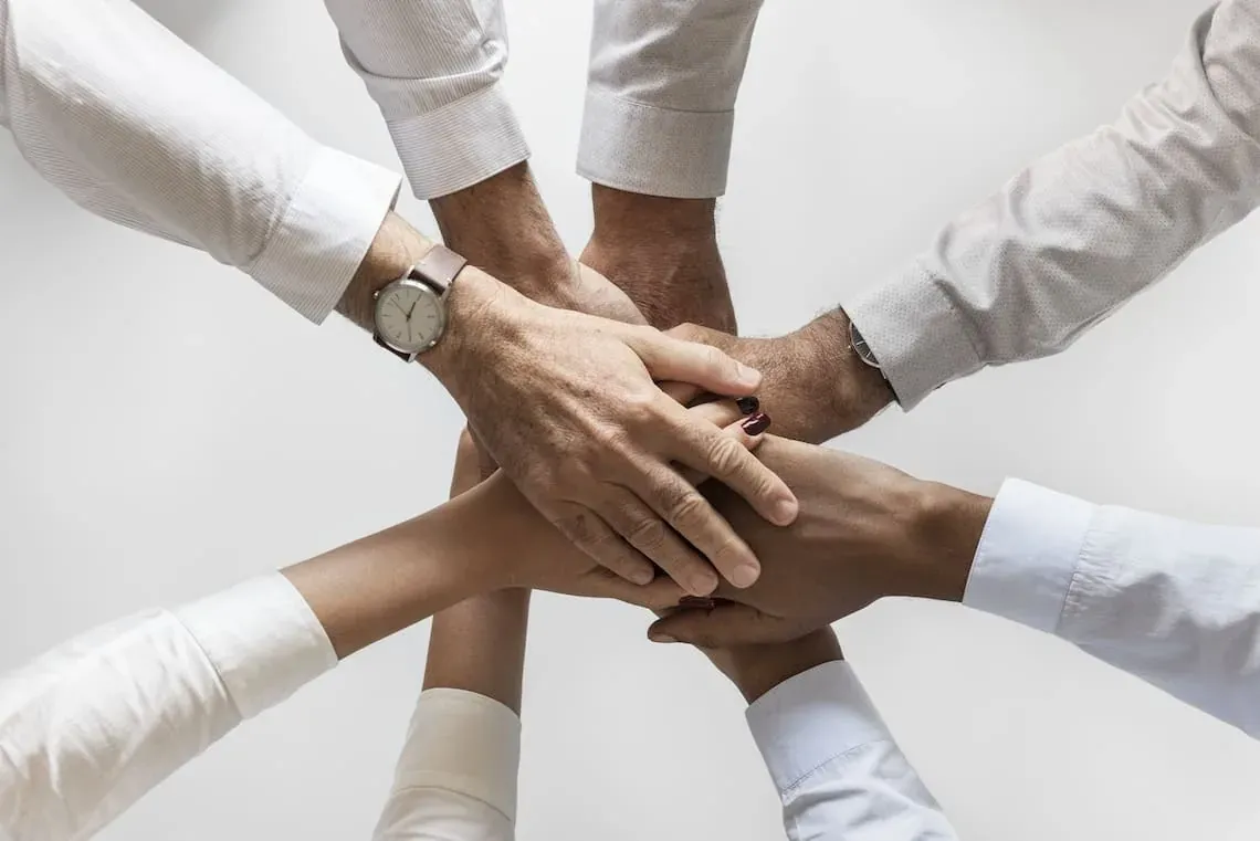 Manos unidas en equipo en ESTIVAL Park Silmar para un servicio excepcional.