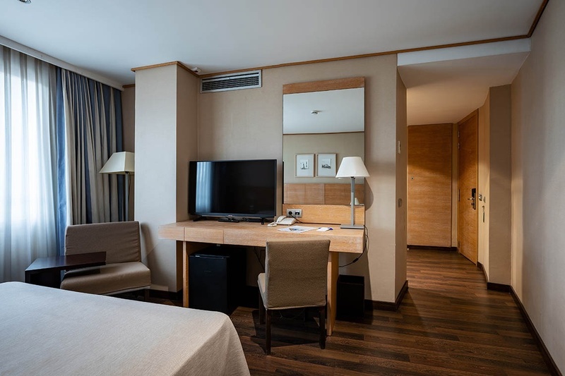 a hotel room with a bed a desk and a television