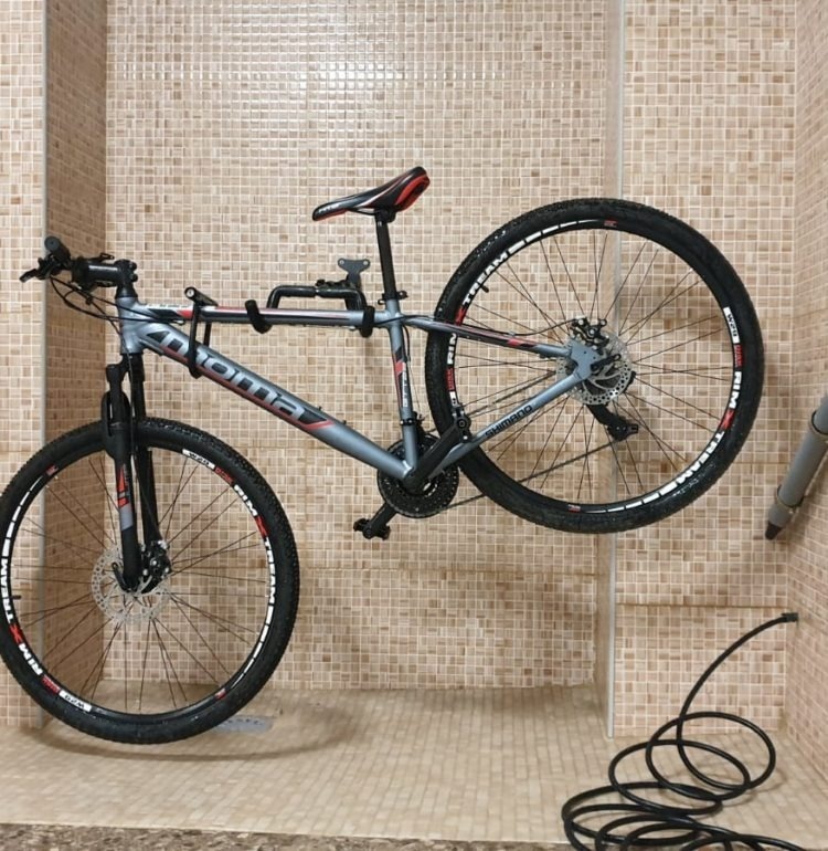 una bicicleta montada en un gancho en una pared de baldosas