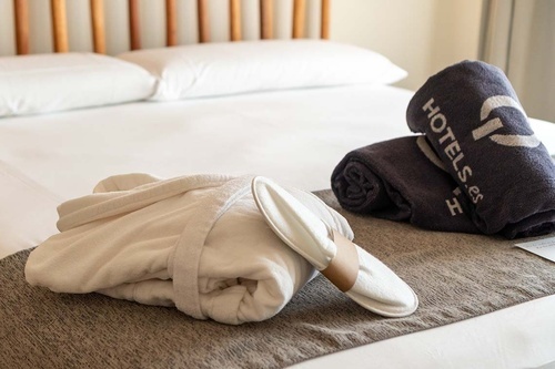 a bed with a bathrobe and towels that say hotels on them