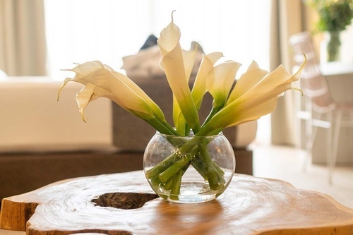 eine Glasvase mit weißen Blumen auf einem Holztisch