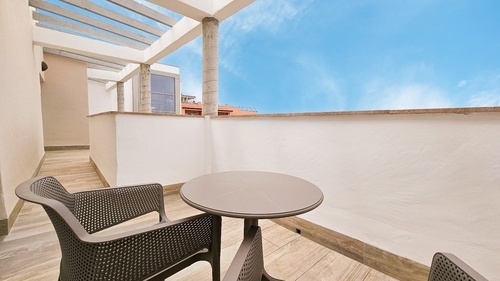 a chair and a table on a balcony with a blue sky in the background