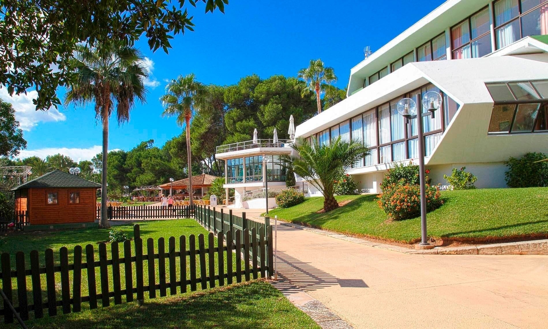 un edificio blanco con muchas ventanas está rodeado de hierba y palmeras