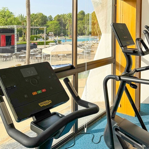un vélo elliptique technogym est assis à côté d' une fenêtre