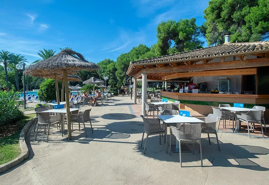 Terraza de hotel con mesas y sillas blancas bajo toldos, ideal para Hotel Exagon Park.