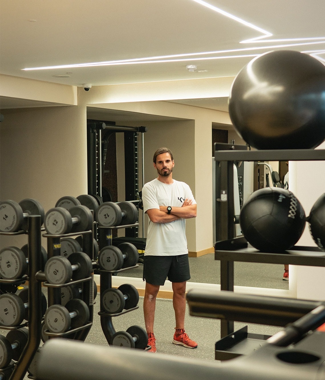 un hombre de pie en un gimnasio con los brazos cruzados