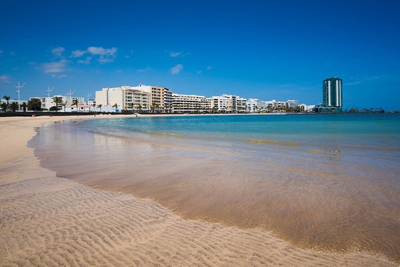 a beach with a tall building in the background