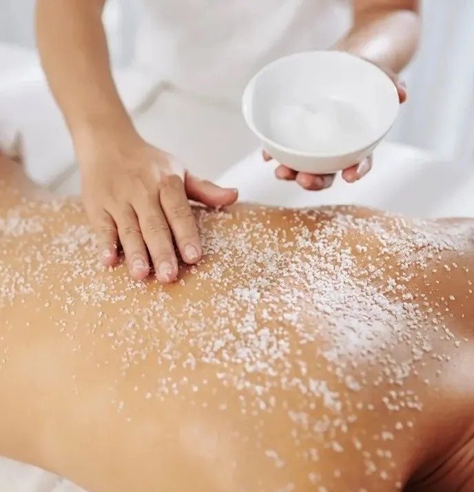 a woman is getting a massage with sea salt on her back