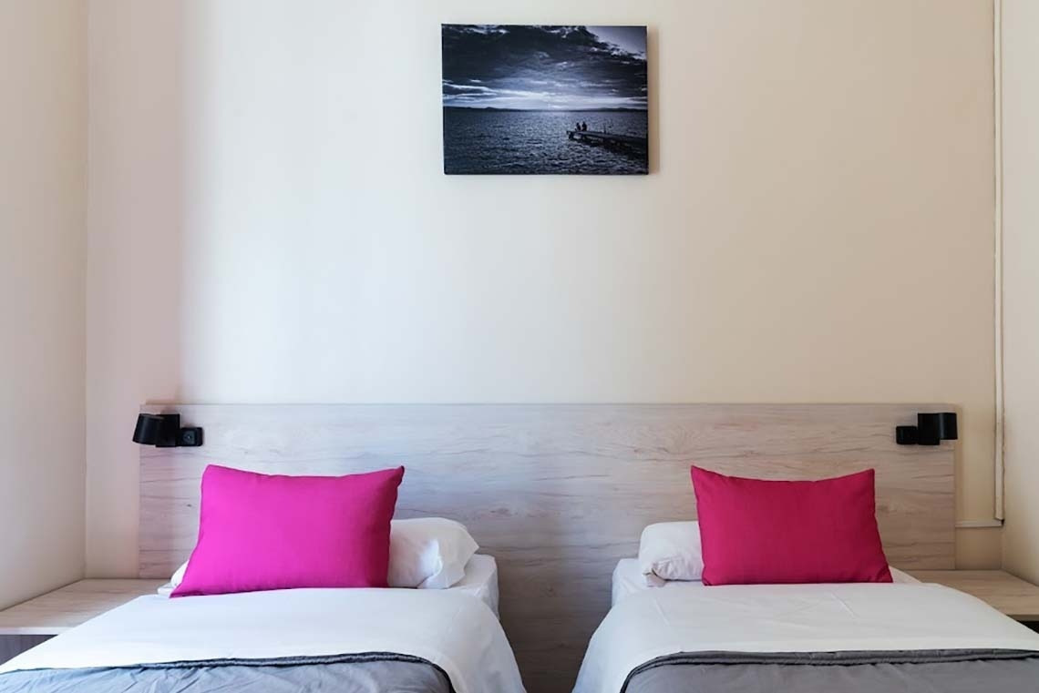 Two twin beds at Red Nest Hostel Valencia | Feet Up | Valencia with pink pillows.