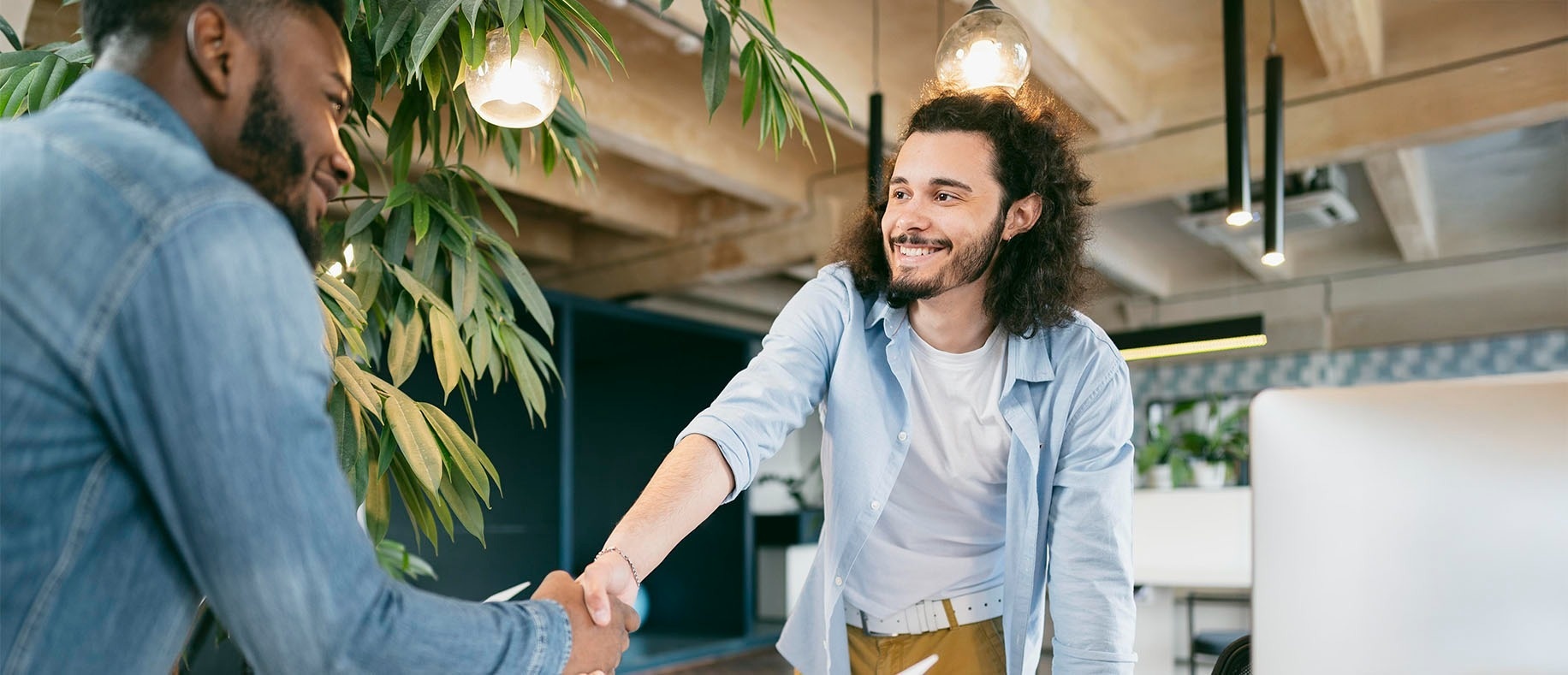 Two businessmen shaking hands, with corporate decor and a relaxed atmosphere for feet up.
