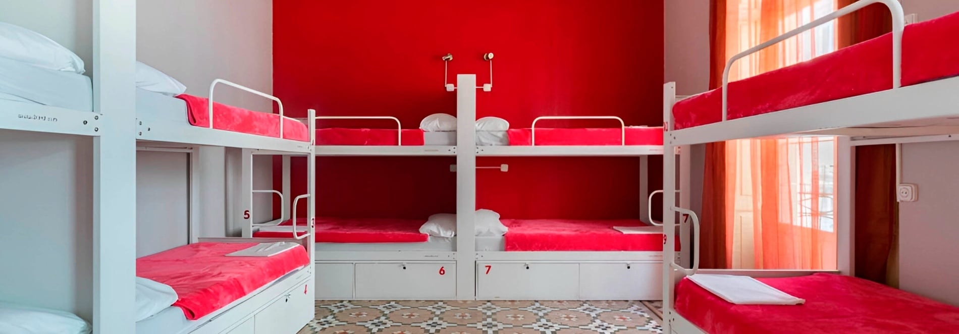 Modern bunk beds with red bedding at Red Nest Hostel Valencia.