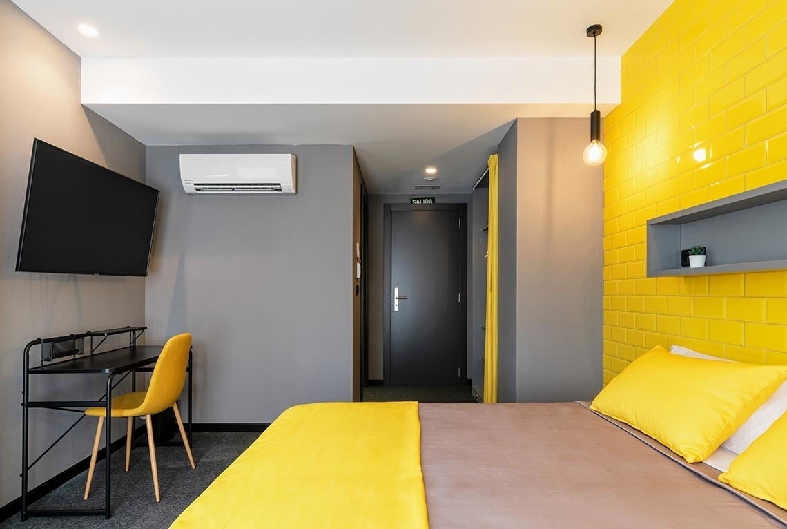 Habitación moderna con cama, escritorio y TV en Nest Style Valencia Hotel. ¡Reserva ya!
