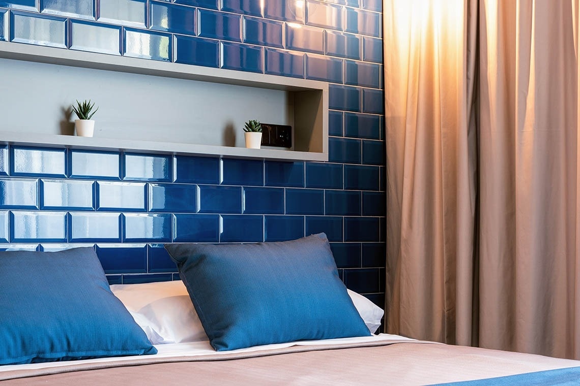 Cama confortable con cojines, pared de azulejos azules y cortinas. Ideal para pies arriba: Corporativa.