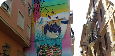 Vibrant mural on narrow street. Put your feet up: Corporativa!