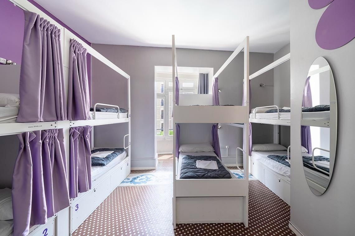 Modern bunk beds with purple curtains and space to relax. Feet up: Corporativa!