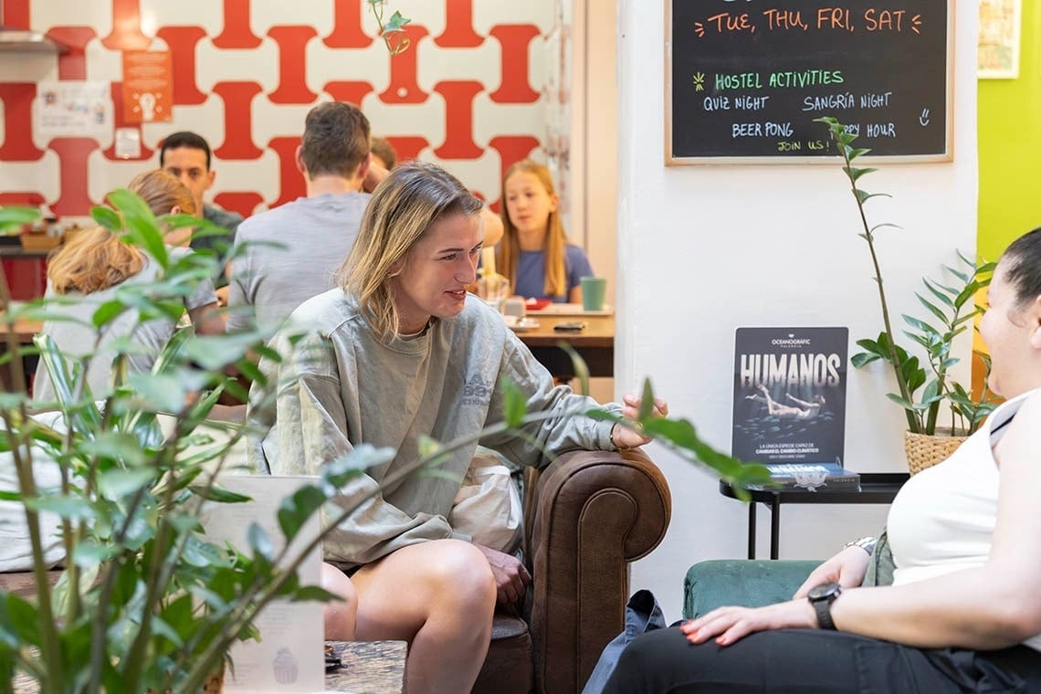 Social area at Hôme Youth Hostel Valencia with people chatting, ideal for Valencia adventures.