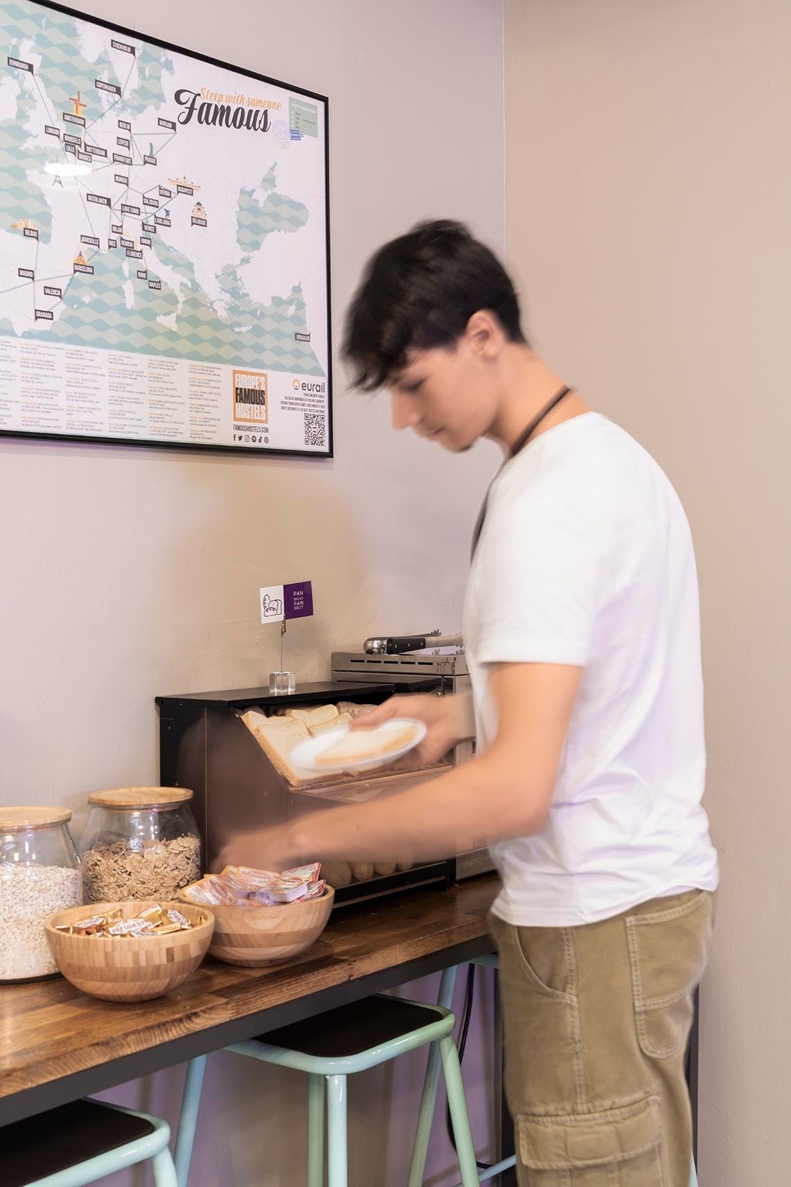 Young man in hostel serving toast, a moment to put your feet up: Corporativa.