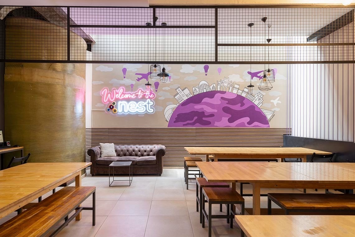 Lounge area with Chester sofas, "Welcome to the Nest" mural, and tables for feet up: Corporativa.