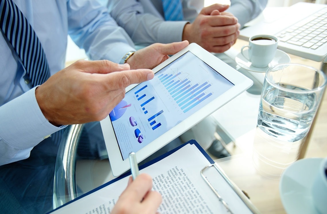 Corporate setting: Professionals review charts on a tablet, feet up.
