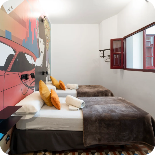 Room with two beds, pop art mural, and "Feet up: Corporativa" style window.