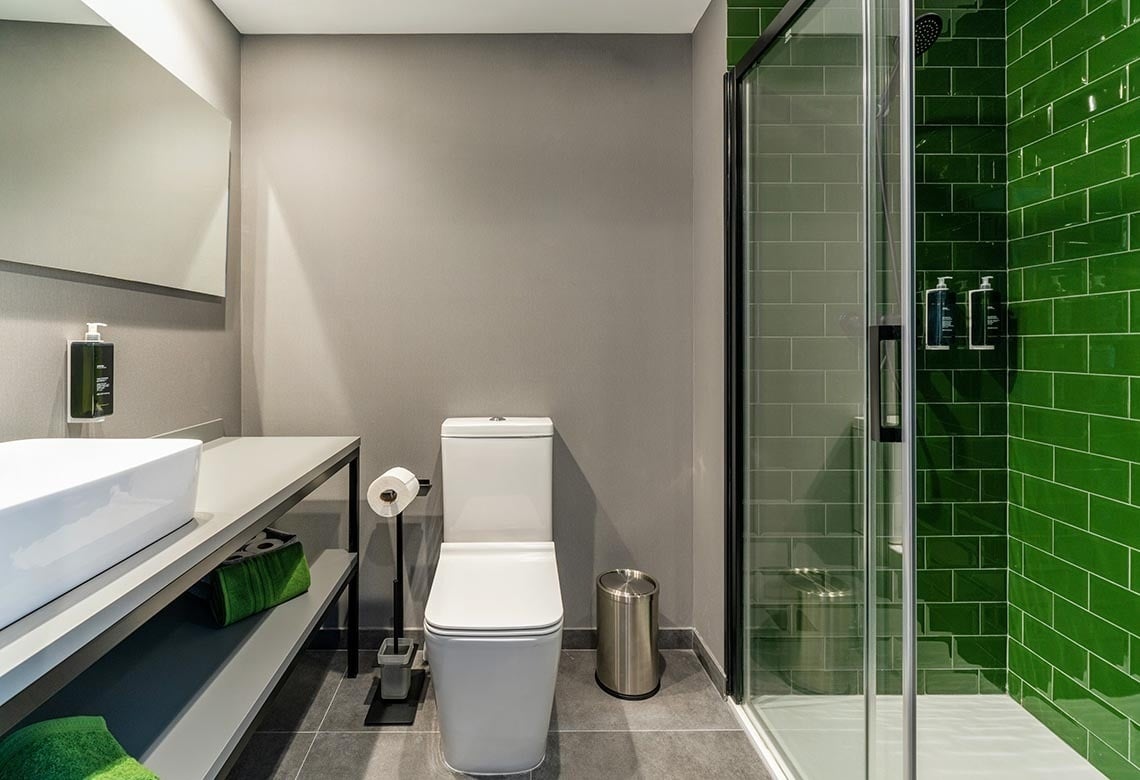 Baño moderno con ducha verde y lavabo en Nest Style Valencia Hotel | Feet Up | Valencia.