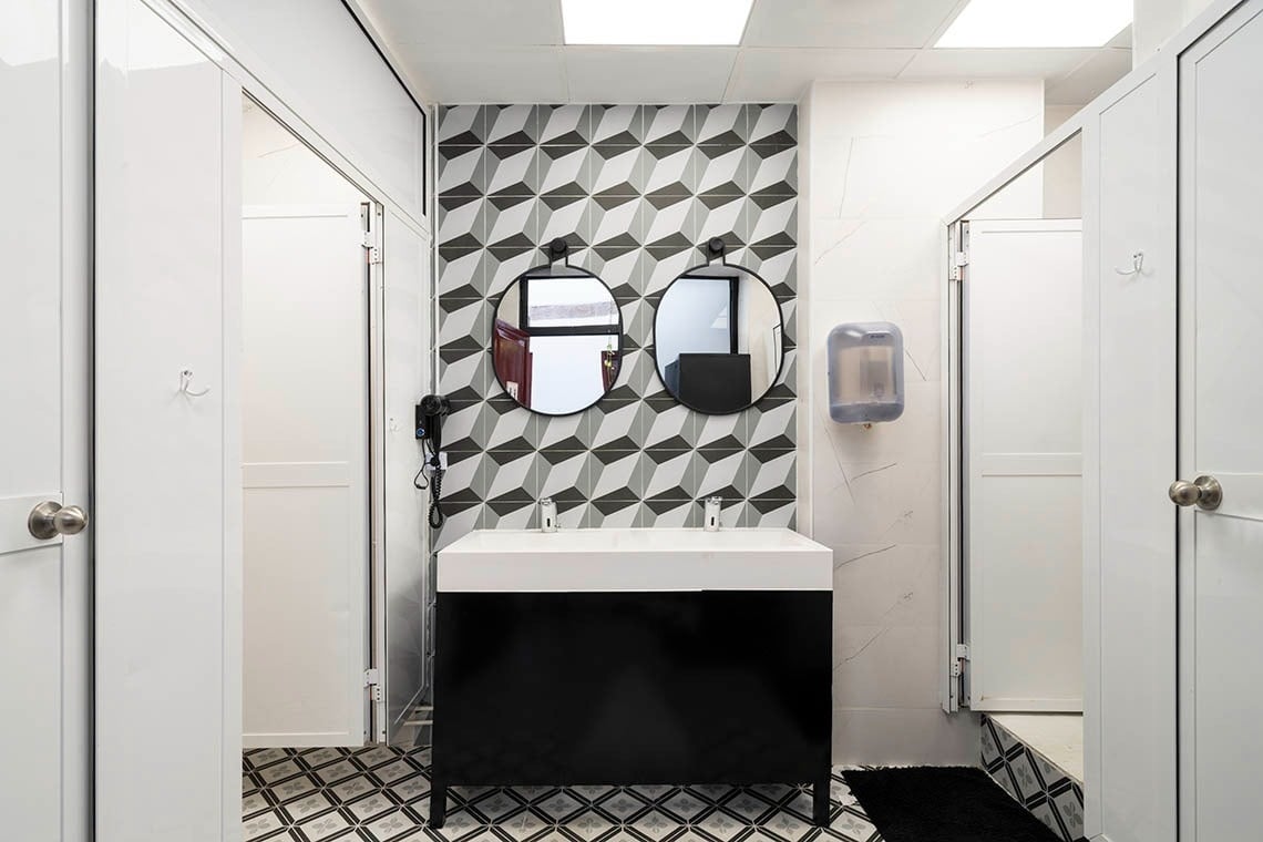 Modern double vanity with geometric tile and circular mirrors at Hôme Youth Hostel Valencia.
