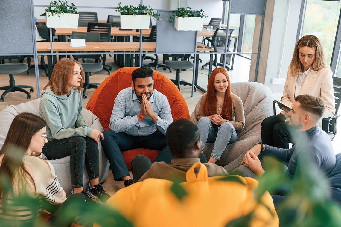 Profesionales relajados, pies arriba, en sala de reuniones corporativa moderna.