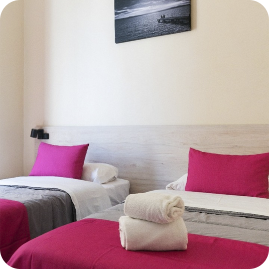 Double room with beds ready to put your feet up: Corporativa. Fuchsia pillows, towels, and more.