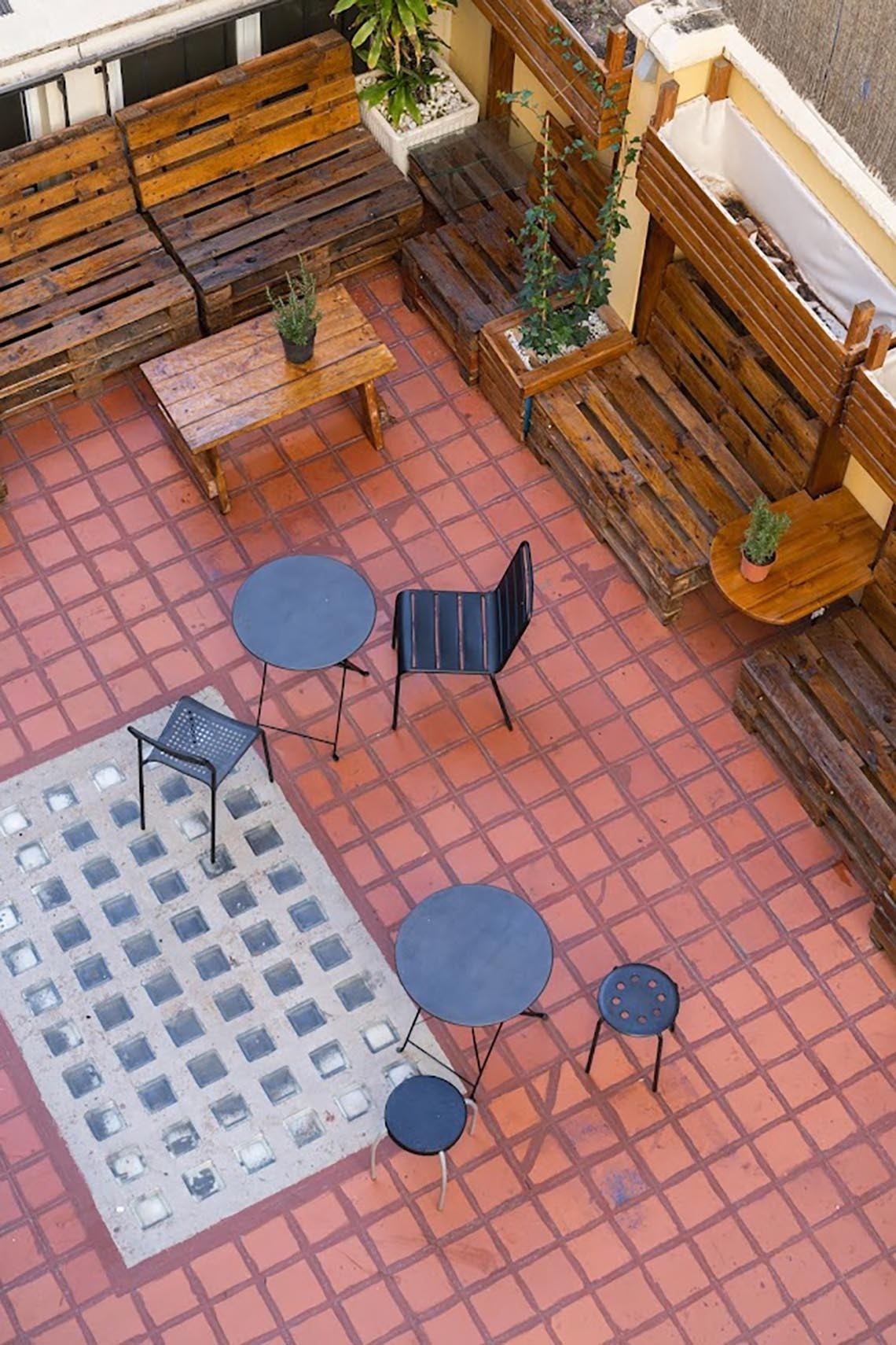 Terraza moderna con asientos de palets y mesas en Purple Nest Hostel Valencia. ¡Reserva ya!