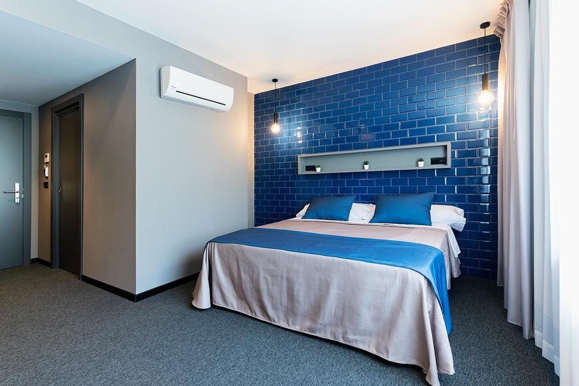 Habitación moderna en Nest Style Valencia Hotel con cama cómoda y pared de azulejos azules. ¡Reserva oficial!