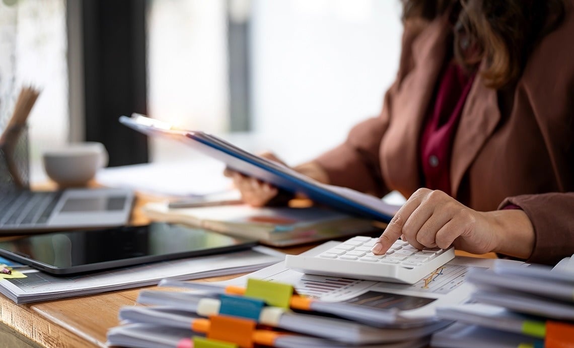 Professional working at desk with calculator and documents. Ideal for business travel.