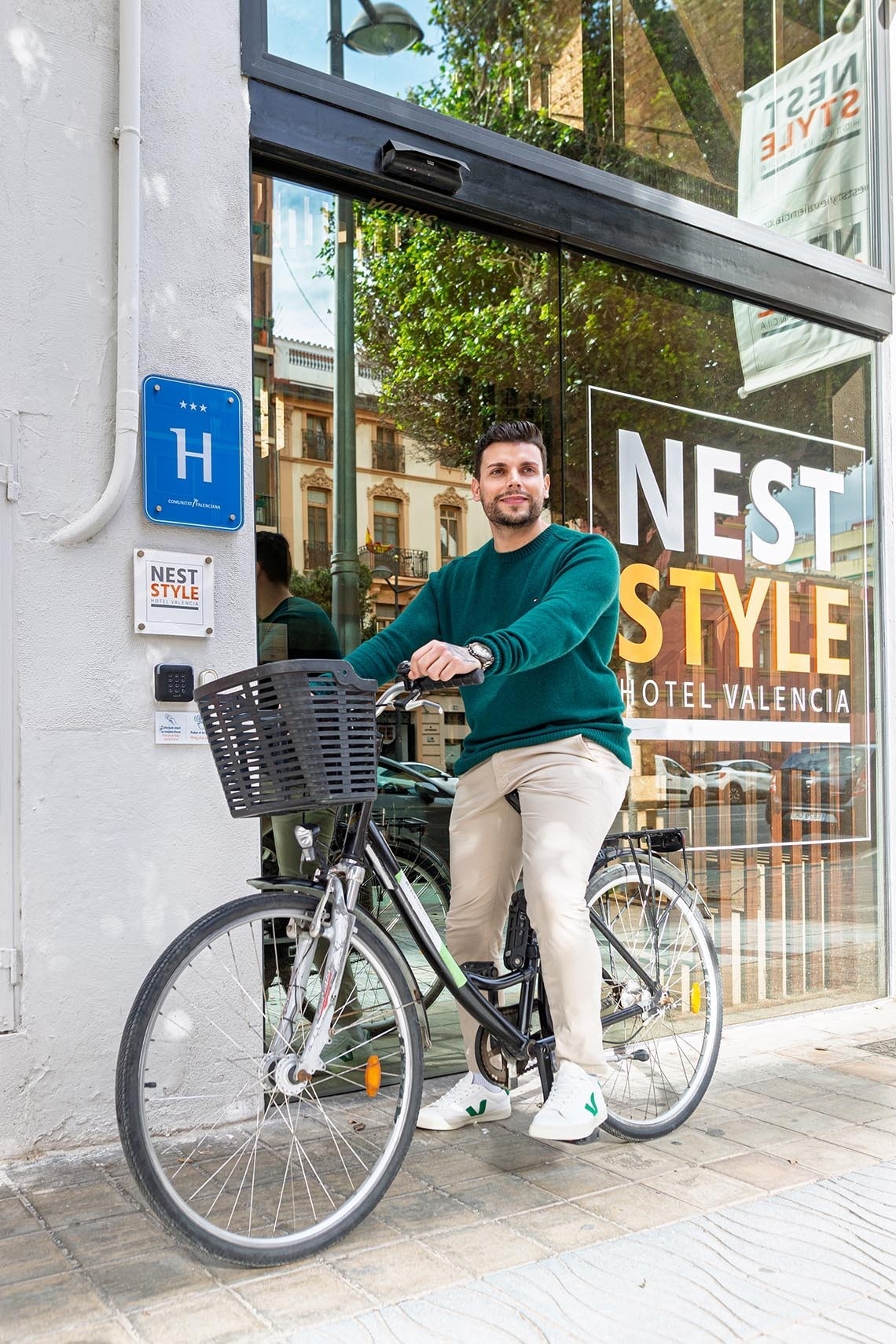 Hombre con bicicleta frente a Nest Style Hotel Valencia. Pies arriba: estancia corporativa.