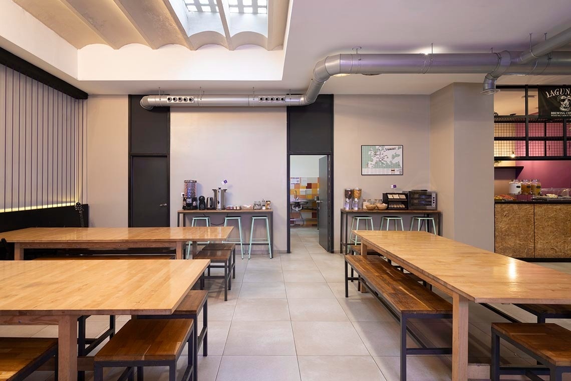 Communal area with wooden tables, perfect for "Feet up: Corporate" relaxation.