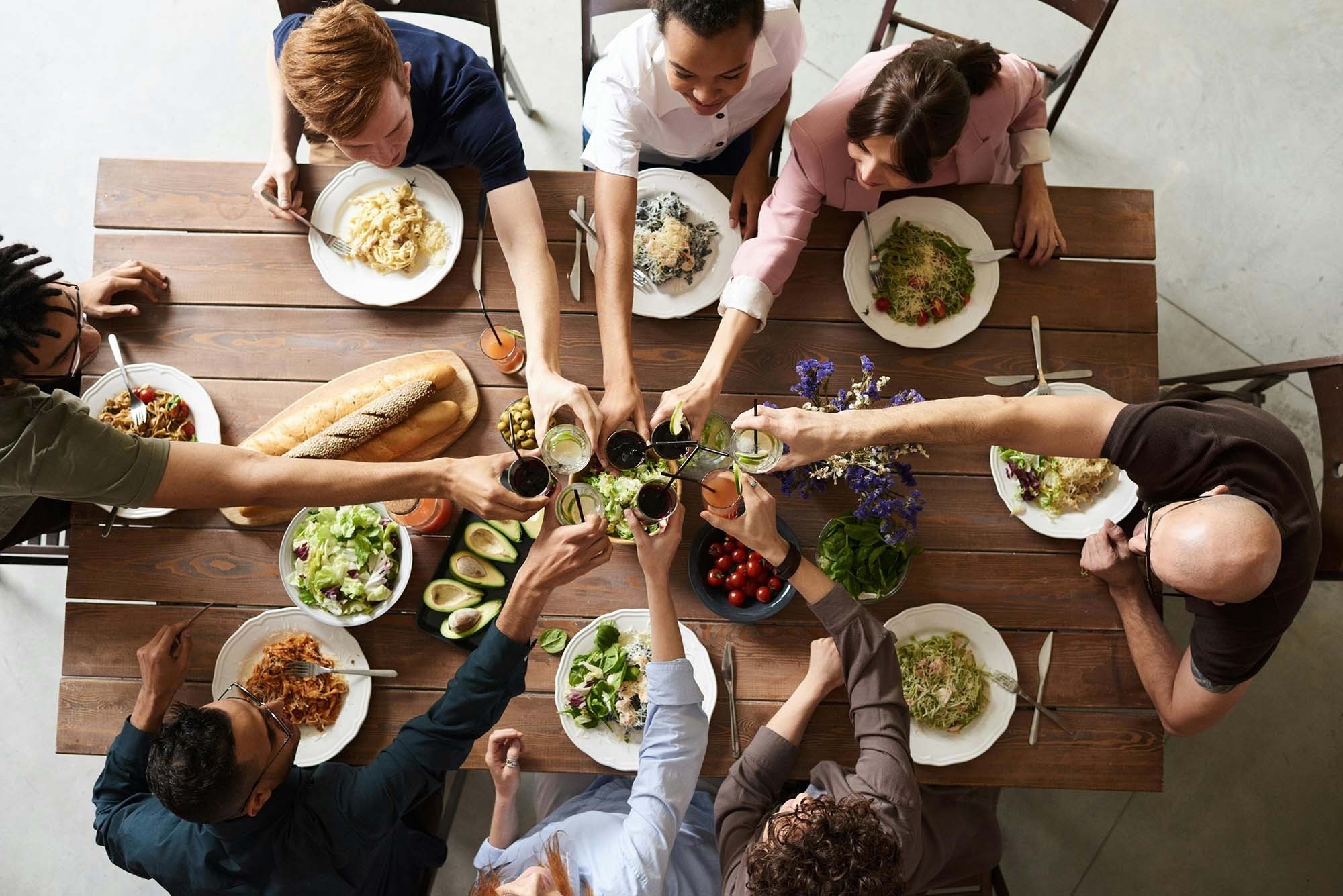 Corporate gathering, people toasting with food on wooden table. Feet up!
