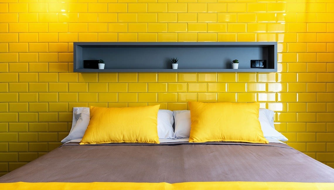 Cama de hotel con cojines amarillos. Descansa tus pies: Corporativa.