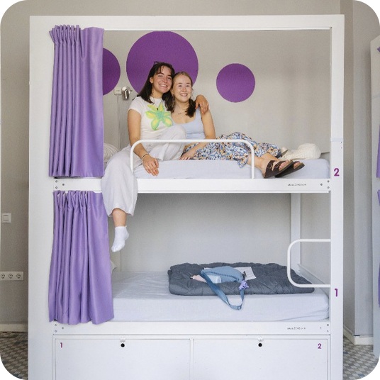 Two friends relaxing, feet up, in hotel bunk beds. Great for groups.