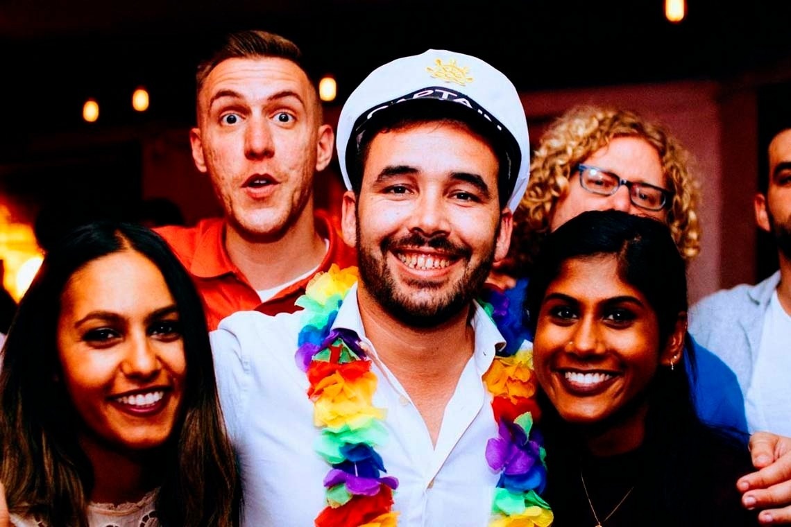 Smiling young people with flower leis, celebrating at a corporate event.