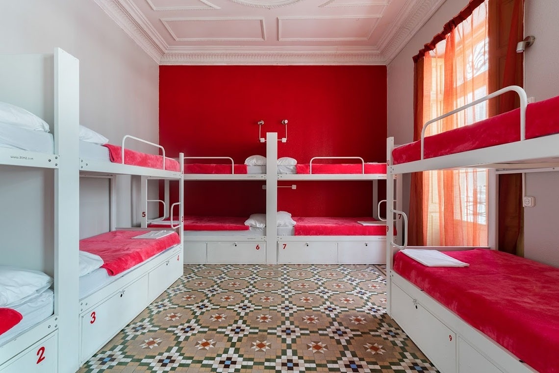 Hostel dorm with red bunk beds and mosaic floor. Feet up: Relax and unwind!