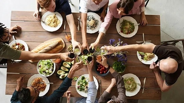 A table with food and people toasting, perfect for a corporate event. Feet up: Corporativa!