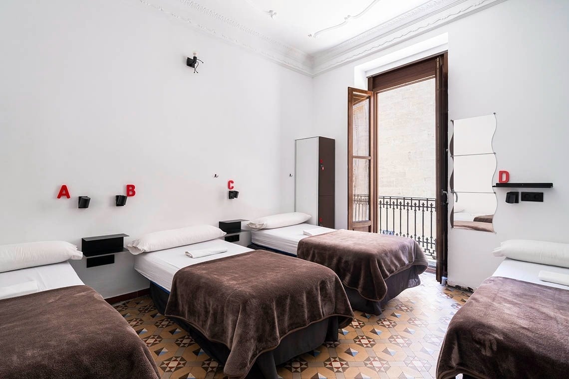 Hôme Youth Hostel Valencia: Twin beds with brown blankets, A-D labels. Valencia Official Website.