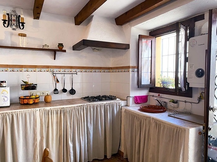 una cocina blanca con una estufa y una ventana