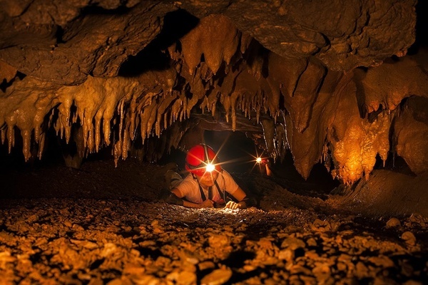 un hombre en una cueva con una linterna en la mano