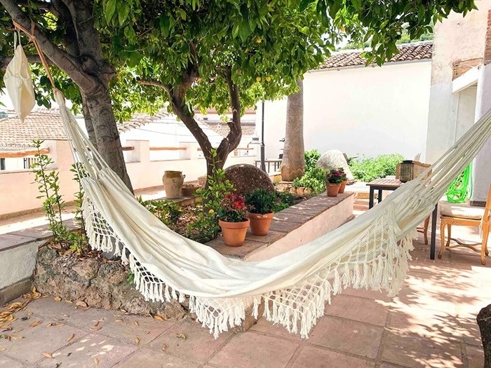 una hamaca blanca cuelga de un árbol en un patio