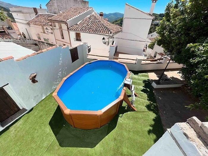 una piscina ovalada está sentada en un patio con edificios blancos en el fondo