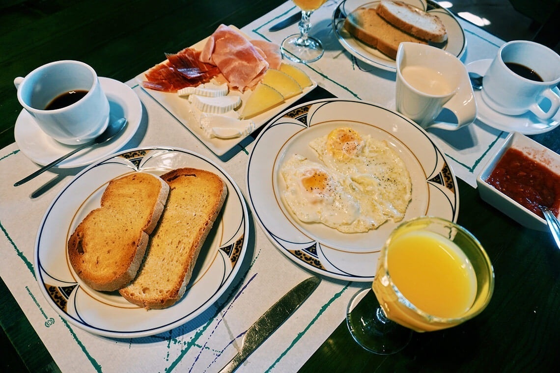 una mesa llena de platos de comida incluyendo huevos fritos y tostadas
