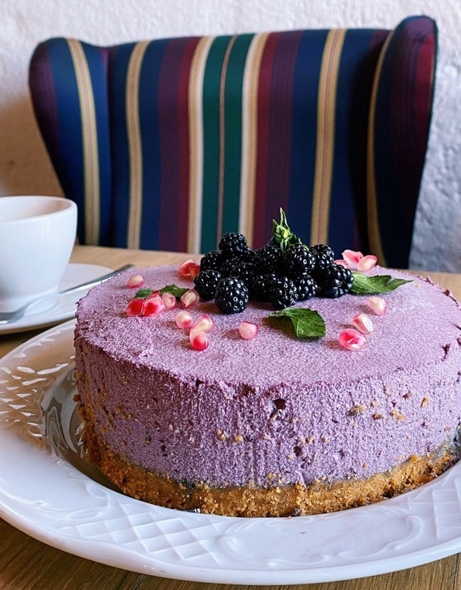 un pastel morado con moras y granadas encima